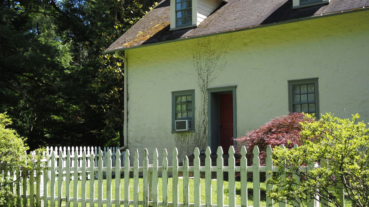 A cottage with a white picket fence and a red door.