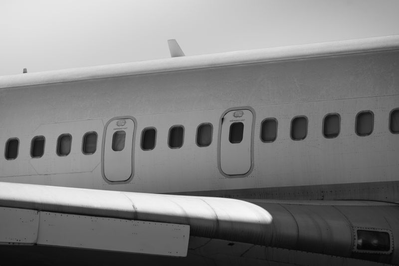Detailed black and white photo of airplane exterior showing fuselage and windows, emphasizing textures.