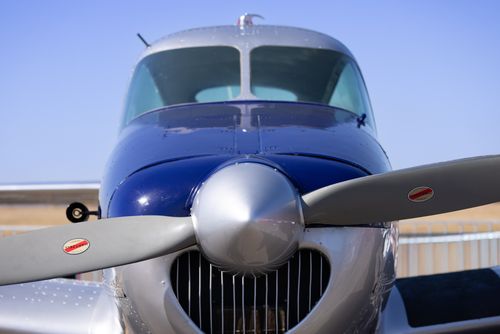 Free Front view of a classic blue and silver airplane with prominent propeller, captured under a clear blue sky. Stock Photo