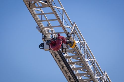 Free Close-up of a crane arm with a red valve against a clear blue sky, showcasing industrial engineering. Stock Photo