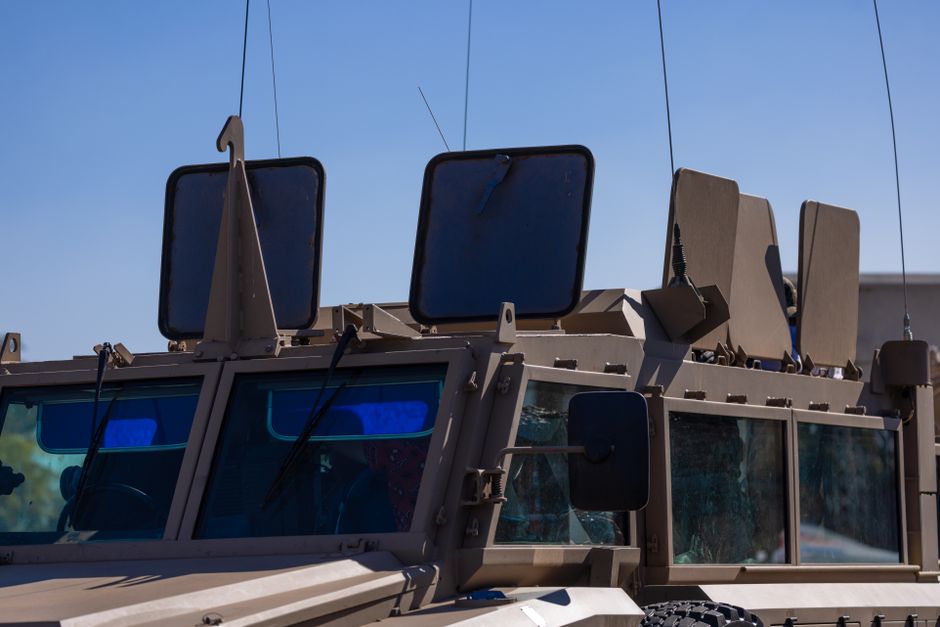 Close-up of military vehicle showing armored details under a clear sky.