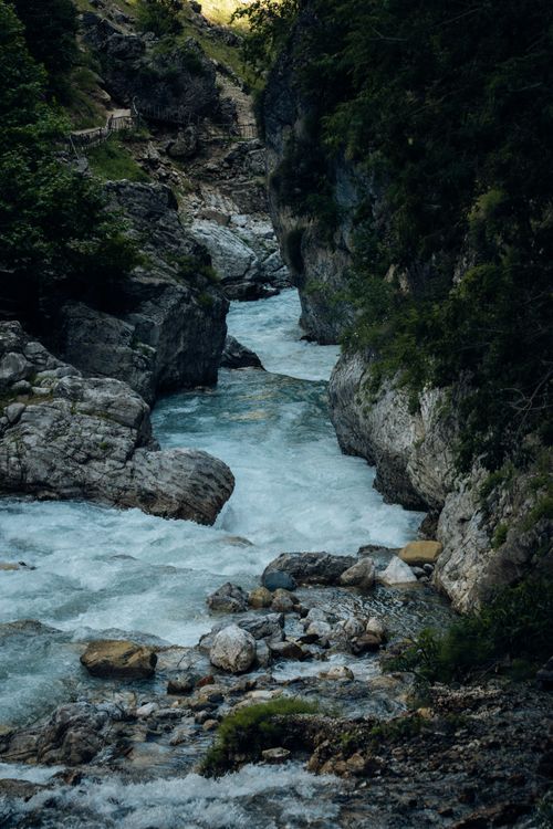 Free Peaceful mountain stream meanders through a rocky gorge surrounded by lush greenery. Stock Photo