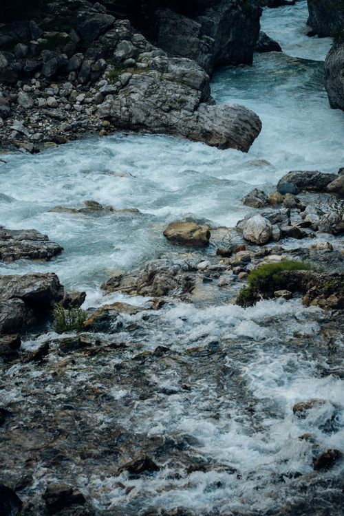 Free A picturesque view of a river flowing through rugged mountain rocks, showcasing nature's beauty. Stock Photo