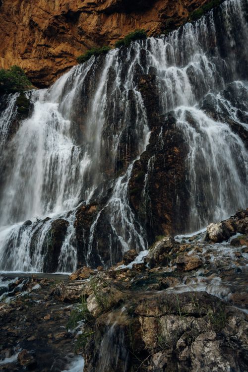 Free A breathtaking waterfall cascading over rugged rocks captured in a dramatic and serene outdoor setting. Stock Photo