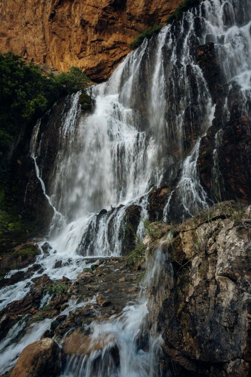 Free Majestic waterfall cascading down rocks surrounded by lush greenery. Stock Photo