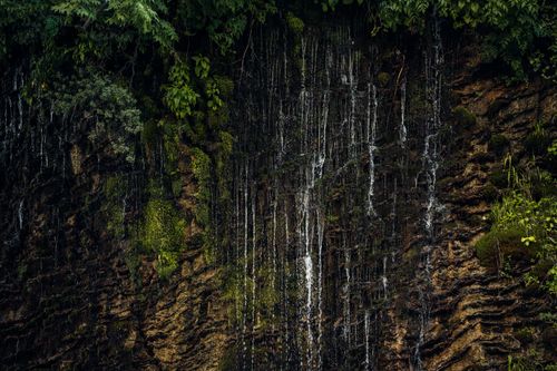 Free Vibrant waterfall cascading over mossy rocks amidst dense green foliage. Stock Photo