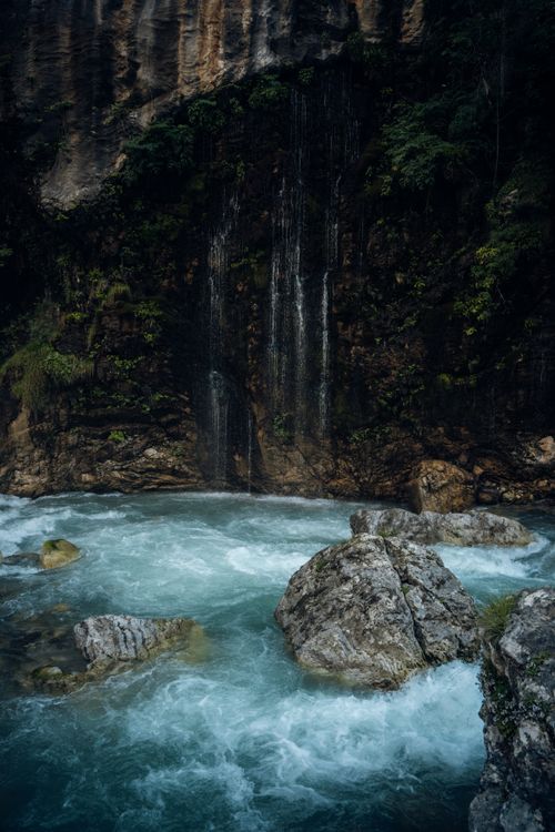 Free Tranquil waterfall cascading over rocks in a lush green canyon, capturing the essence of natural beauty and serenity. Stock Photo