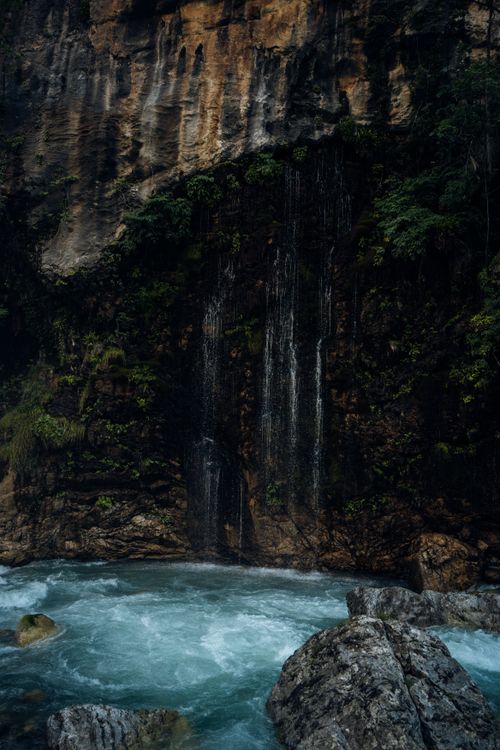 Free Peaceful waterfall cascading down rocky cliffs into a clear blue pool in a tranquil natural setting. Stock Photo
