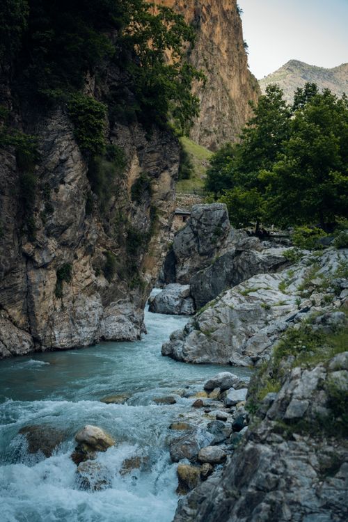 Free Tranquil mountain river cascading through rocky gorge with lush greenery, creating a serene natural landscape. Stock Photo
