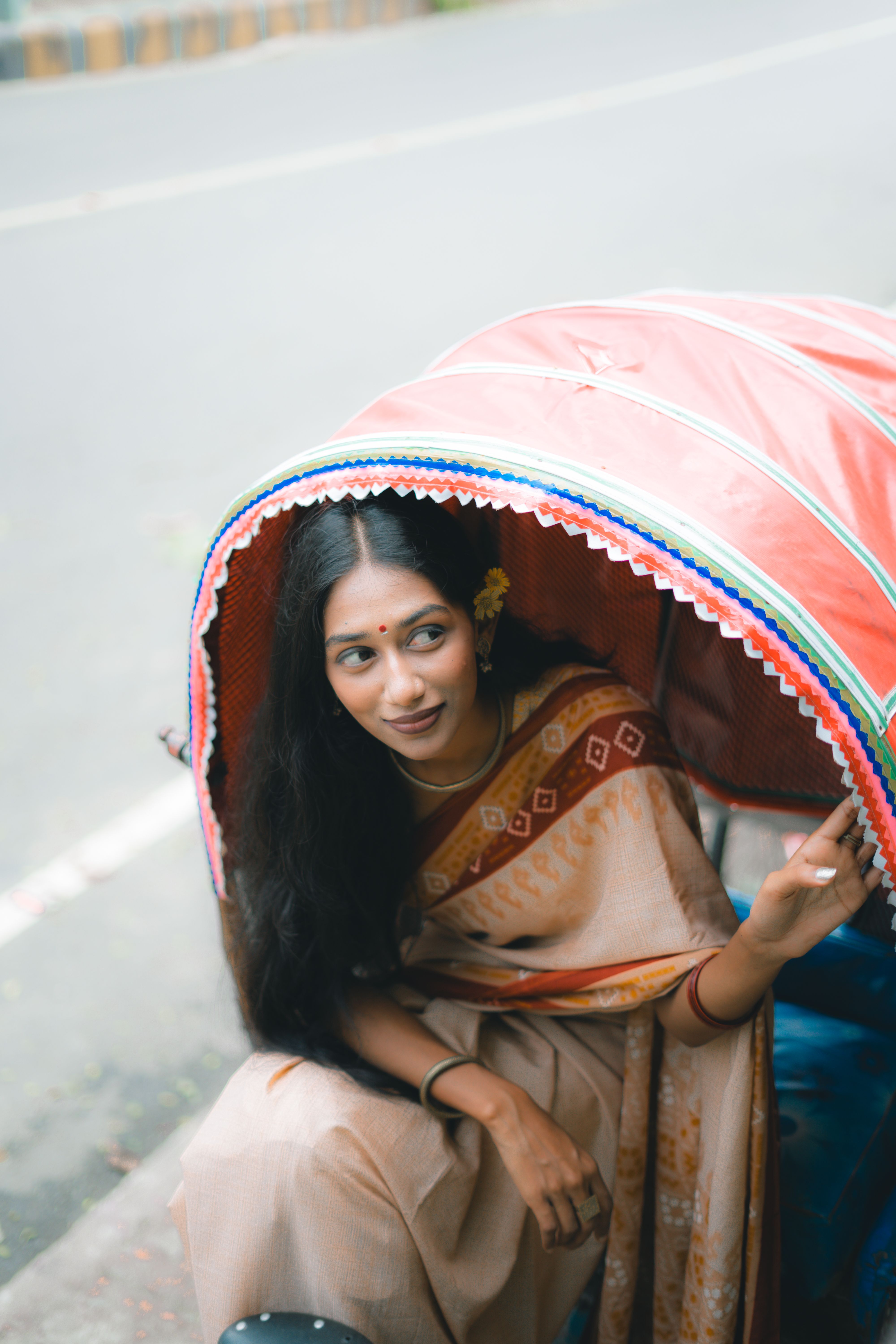 A young woman in traditional attire sits inside a vibrant rickshaw, showcasing cultural elegance.