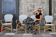 Trendy woman in floral trousers enjoys a sunny day at an outdoor café in Tallinn, Estonia.