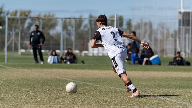 Teen soccer player preparing a kick during a match on a sunny day.