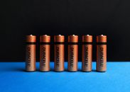 A lined up set of AA batteries with black and blue background.
