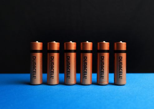 A lined up set of AA batteries with black and blue background.