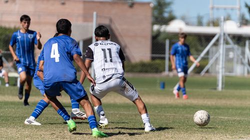 Free Boys playing soccer, one team in white and the other in blue uniforms, on a crisp sunny day. Stock Photo