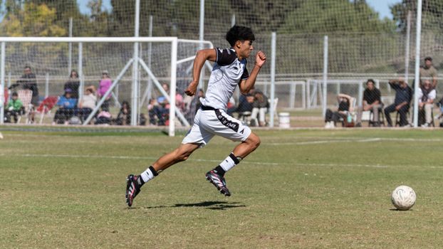 Young soccer player sprinting on a sunny outdoor field during a match.