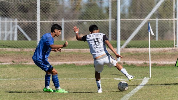Two soccer players in action during a match near the corner flag on a sunny day.