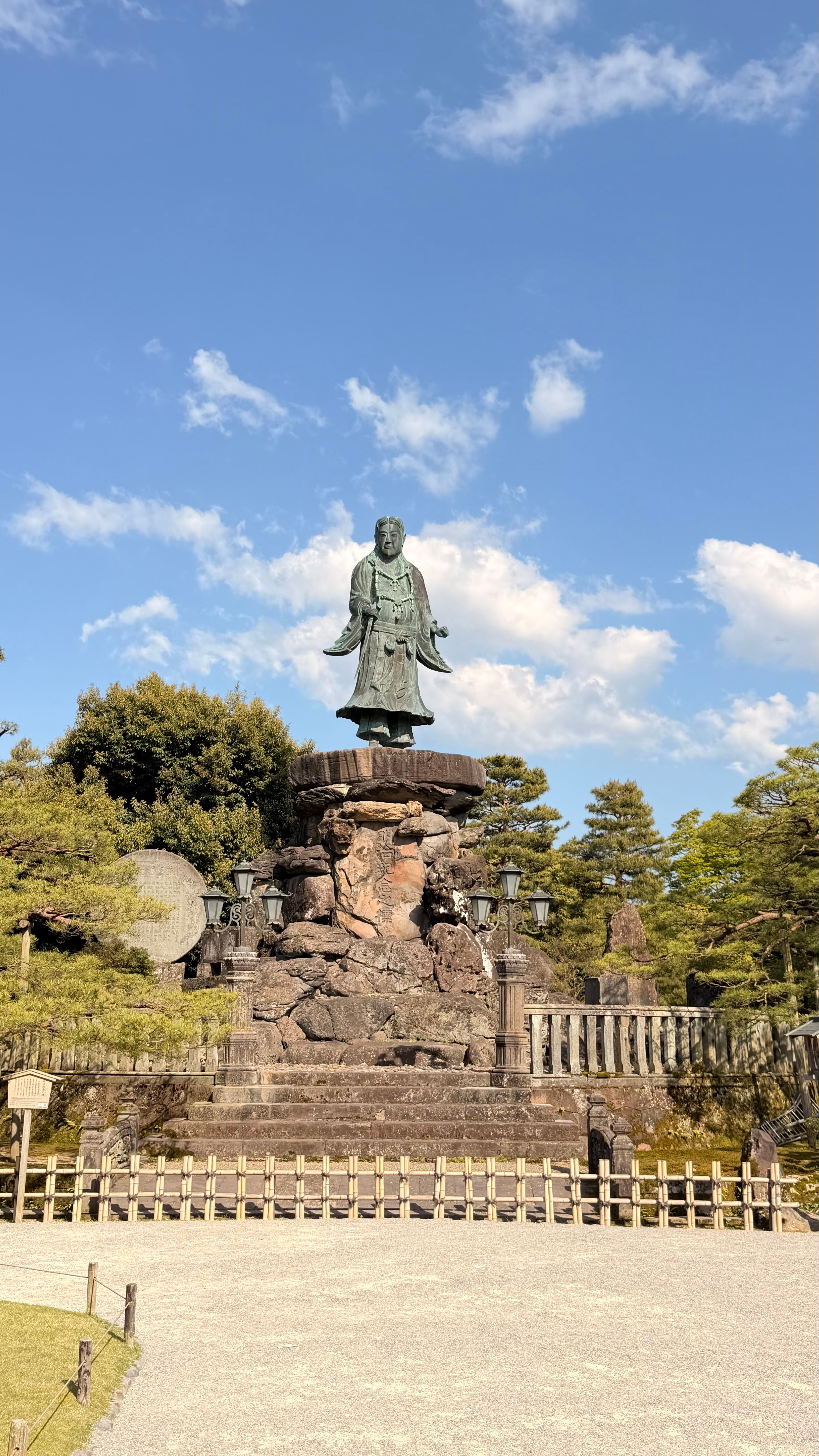 A scenic view of a historic statue in a Japanese garden, Kanazawa.