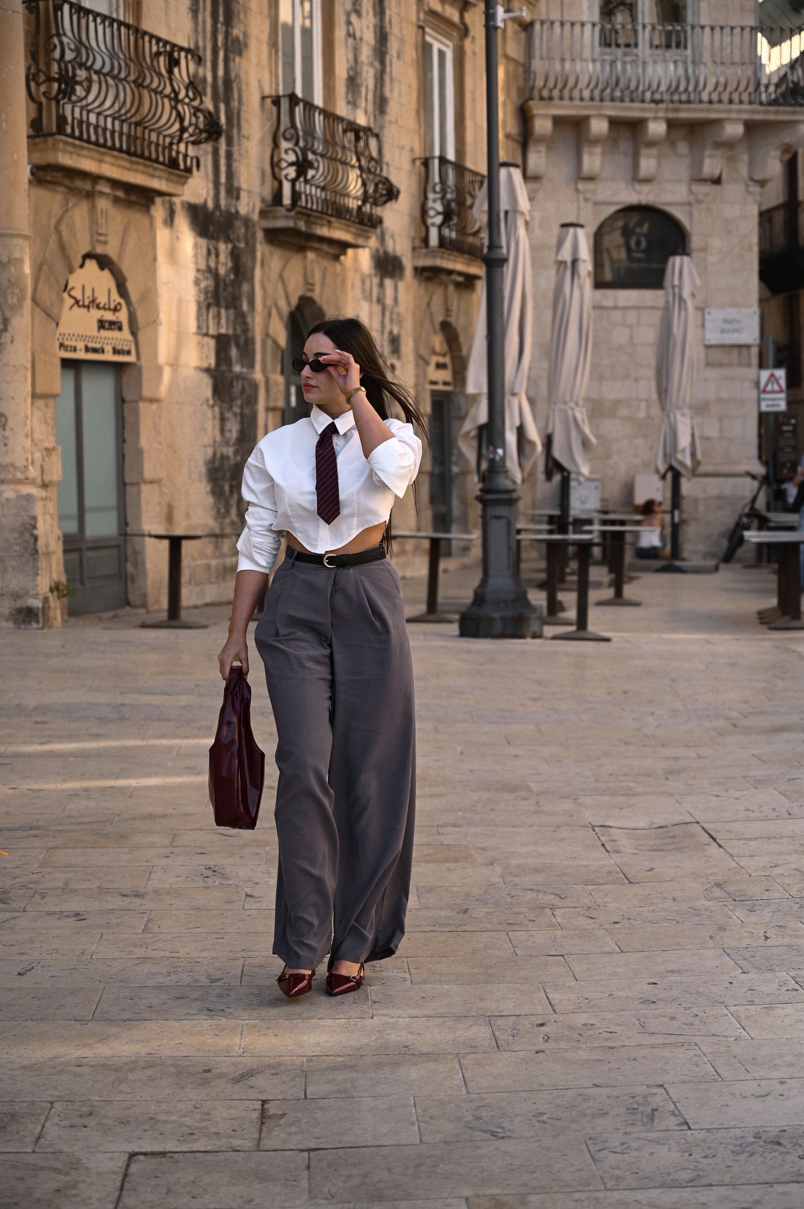 An elegant woman walking in a historic European street in wide-leg trousers