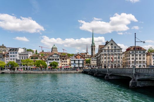 Charming view of Zurich with historic buildings along the Limmat River under a clear blue sky.