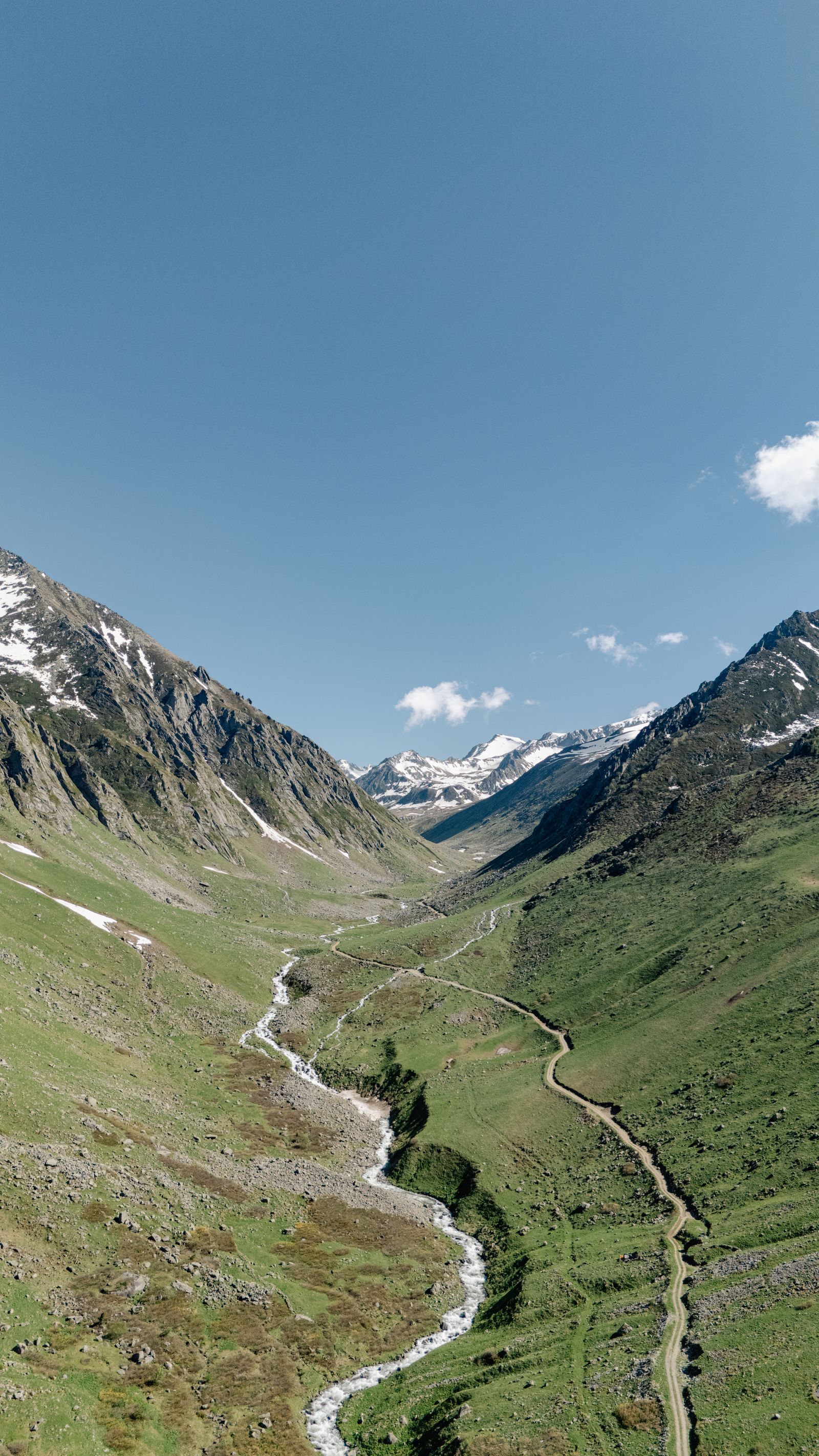 Scenic Alpine Valley with Flowing Stream and Snowy Peaks · Free Stock Photo