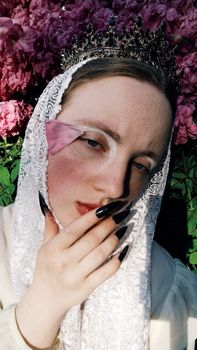 A creative portrait featuring a woman in a lace veil with a floral crown against a pink hydrangea backdrop.