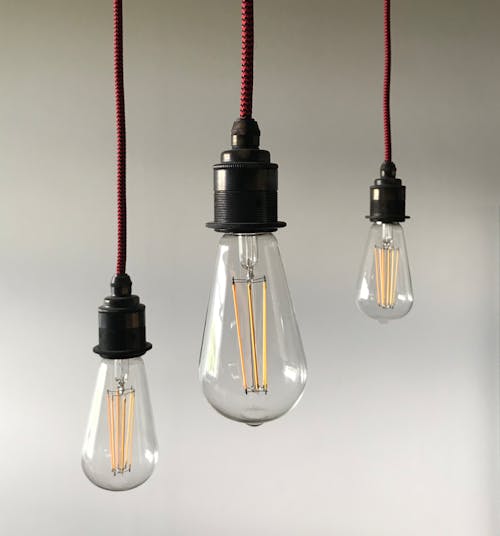 Vintage light bulbs in different sizes hanging on ceiling against blurred white background