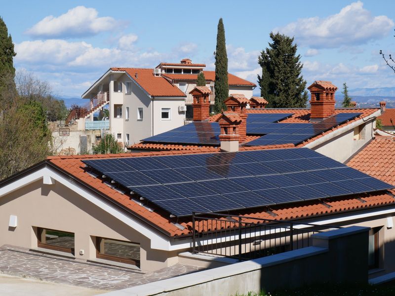 Solar panels on red tile rooftops in a sunny neighbourhood