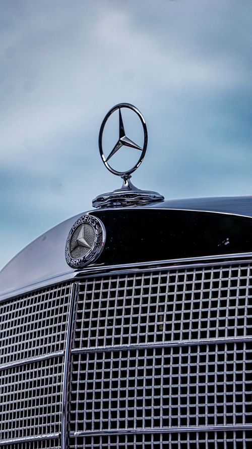 Free Vintage car emblem and grille with blue sky background, showcasing classic design. Stock Photo