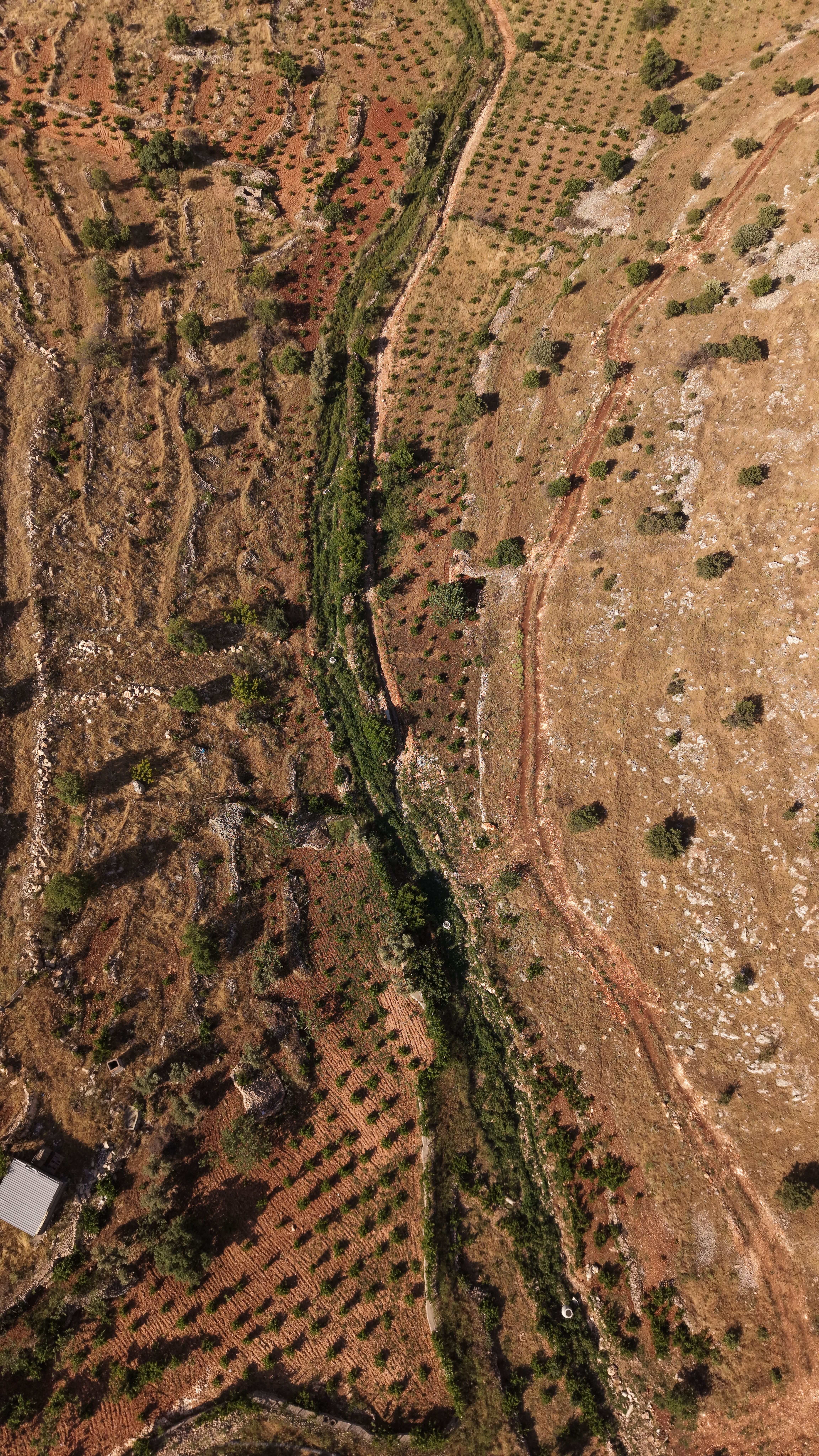 Aerial shot of Mardin, Türkiye, showcasing rugged, semi-arid landscape with unique terrain features.