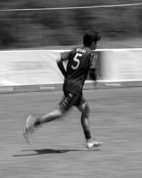 Monochrome blurred image of a soccer player in motion on the field.