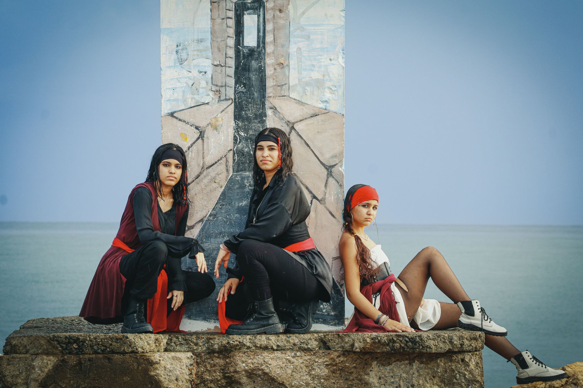 Three women dressed in pirate costumes pose outdoors against a coastal backdrop in Puerto Rico.