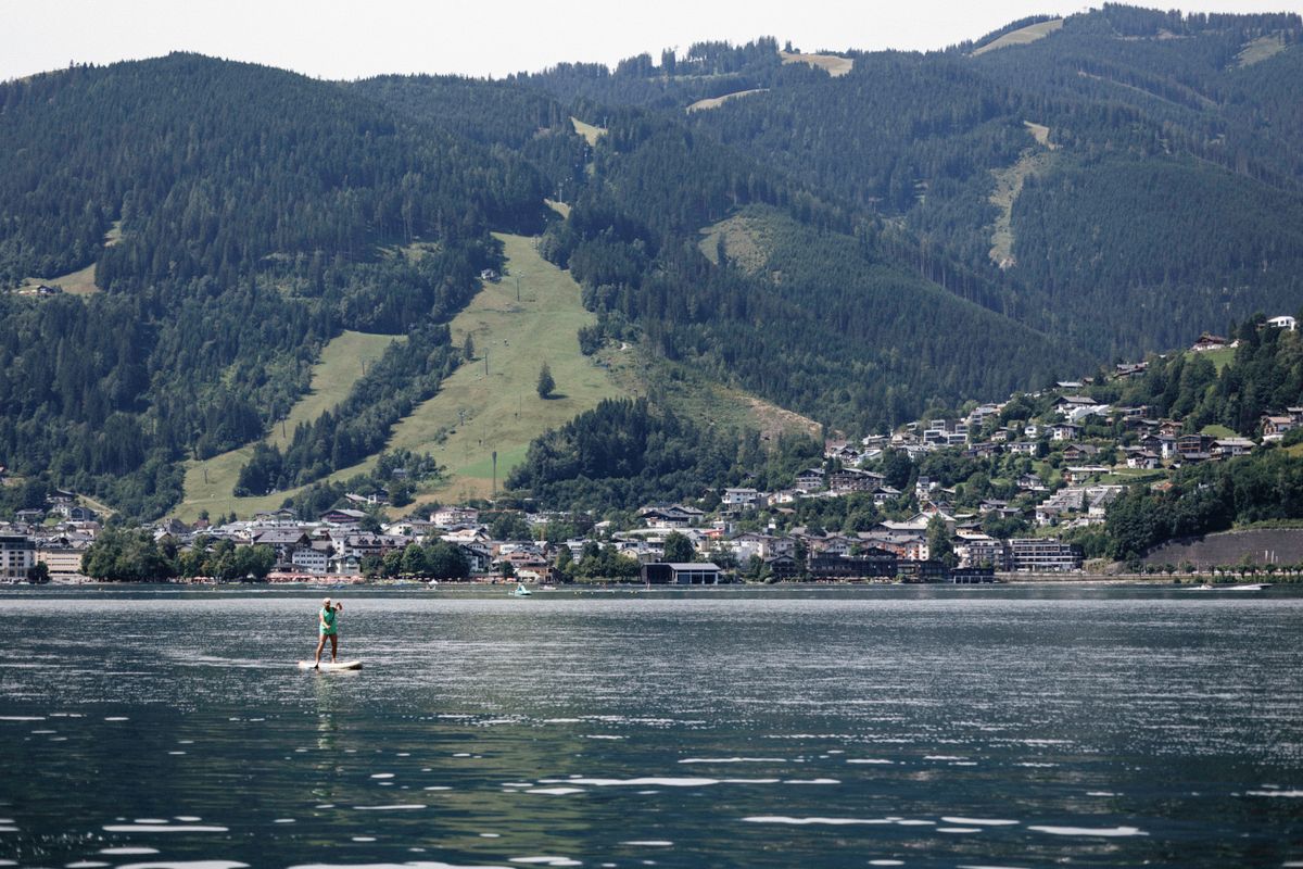 Paddleboarder on Lake Zell with the town and Alps behind