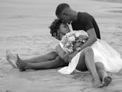 一张黑白照片中，一对夫妇在海滩上分享着温柔时刻，表达了爱与亲密