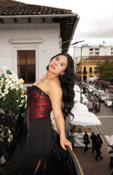 An elegant woman with dark hair and floral dress detail posing outdoors on a busy street in Cuenca, Ecuador.