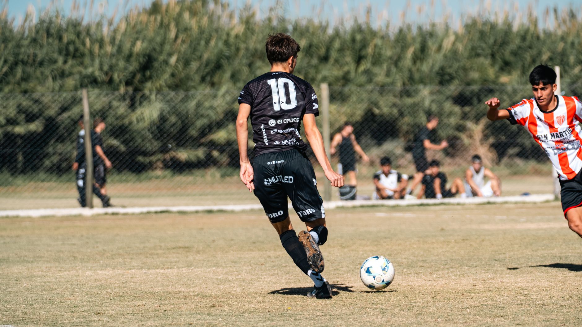 A dynamic soccer scene with young athletes striving for the ball in a local match outdoors.