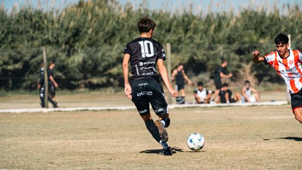 A dynamic soccer scene with young athletes striving for the ball in a local match outdoors.