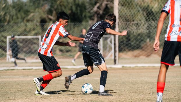 Two young male soccer players competing intensely on an outdoor field during the day.