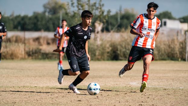 Teen soccer players competing in a lively match on a sunny day.