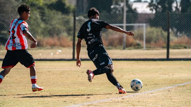 Dynamic football scene capturing two players in action during a match on a sunny field.