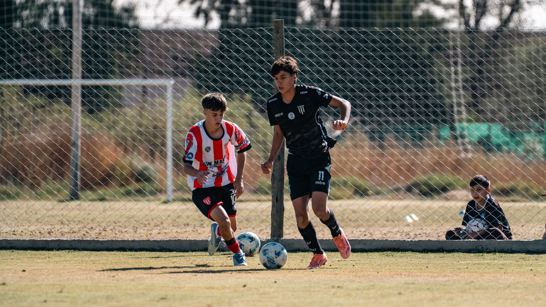 A youth footballer changing direction sharply while dribbling through blue cones
