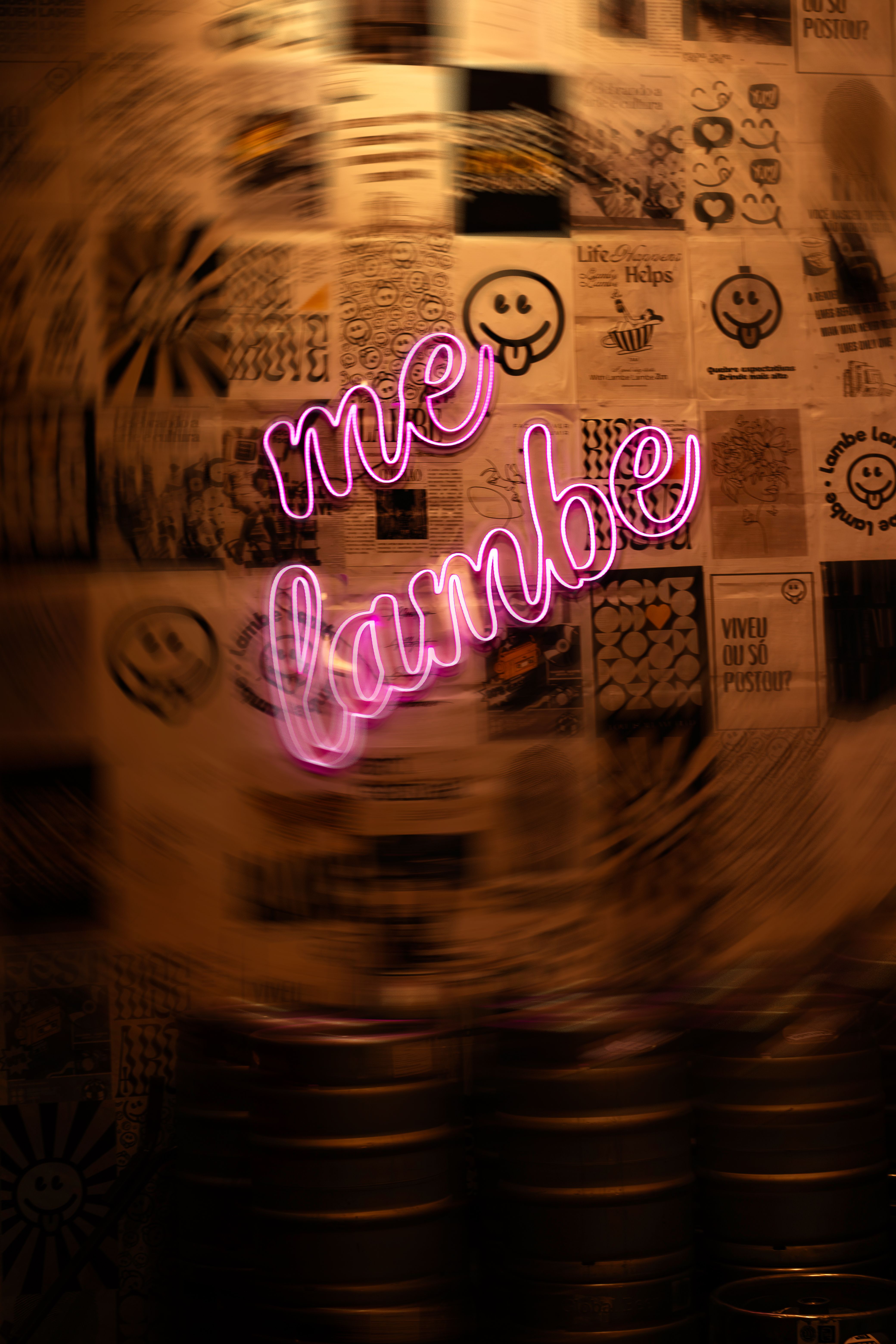 Close-up of a vibrant pink neon sign against a retro poster-covered wall.