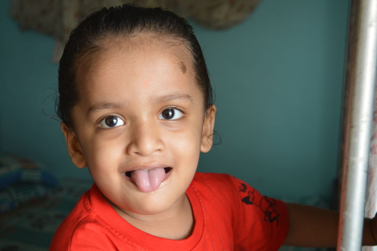 a happy child playfully sticking out their tongue indoors capturing jo