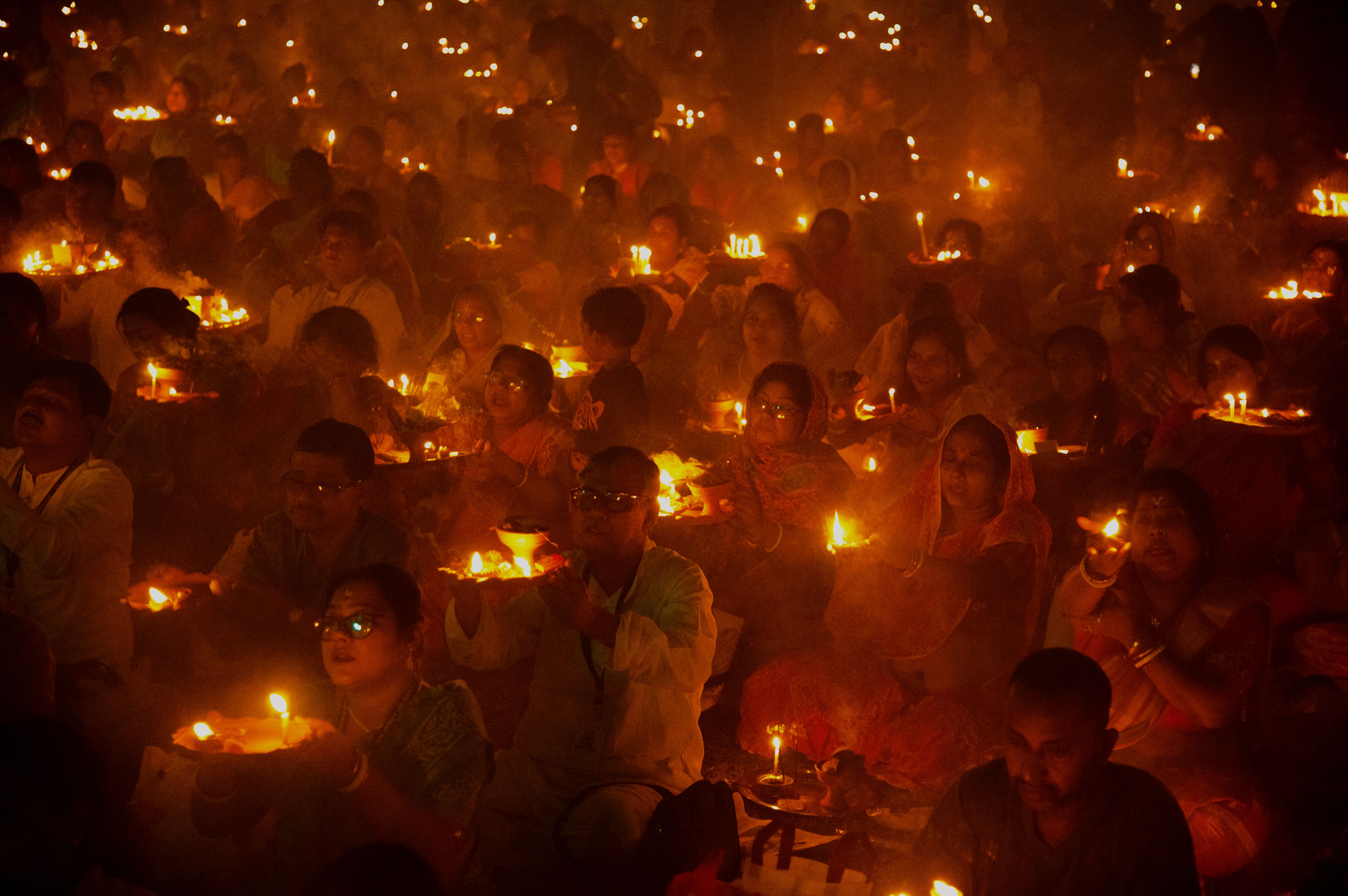 People gathered for a candlelight ritual, holding candles in a warm, glowing atmosphere.