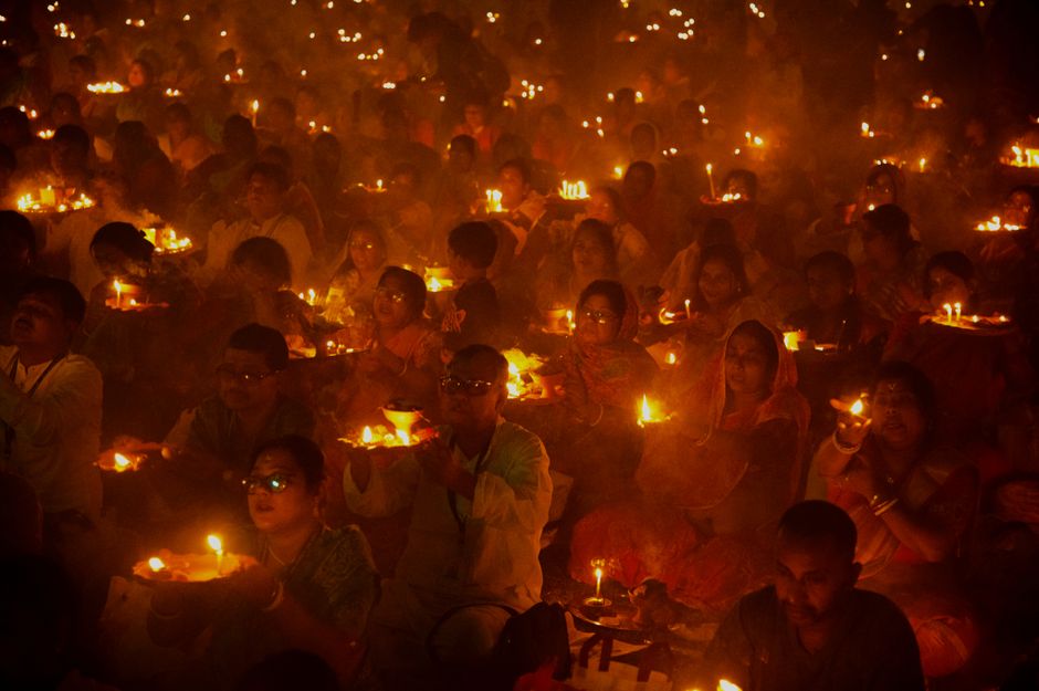 People gathered for a candlelight ritual, holding candles in a warm, glowing atmosphere.