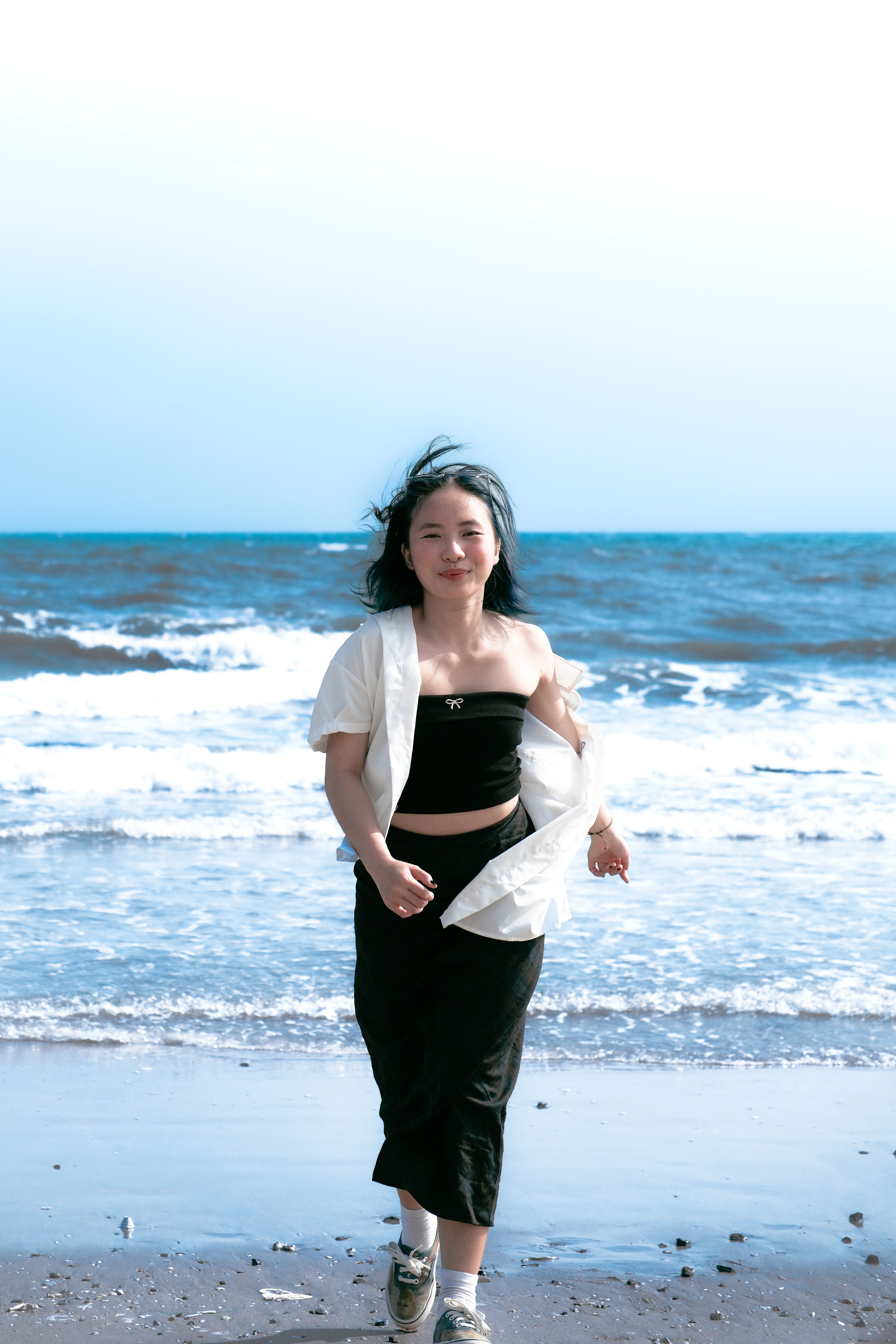 Asian woman walking joyfully along the shoreline in Vung Tau, Vietnam.