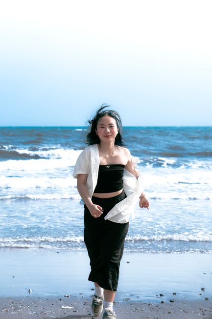Asian woman walking joyfully along the shoreline in Vung Tau, Vietnam.