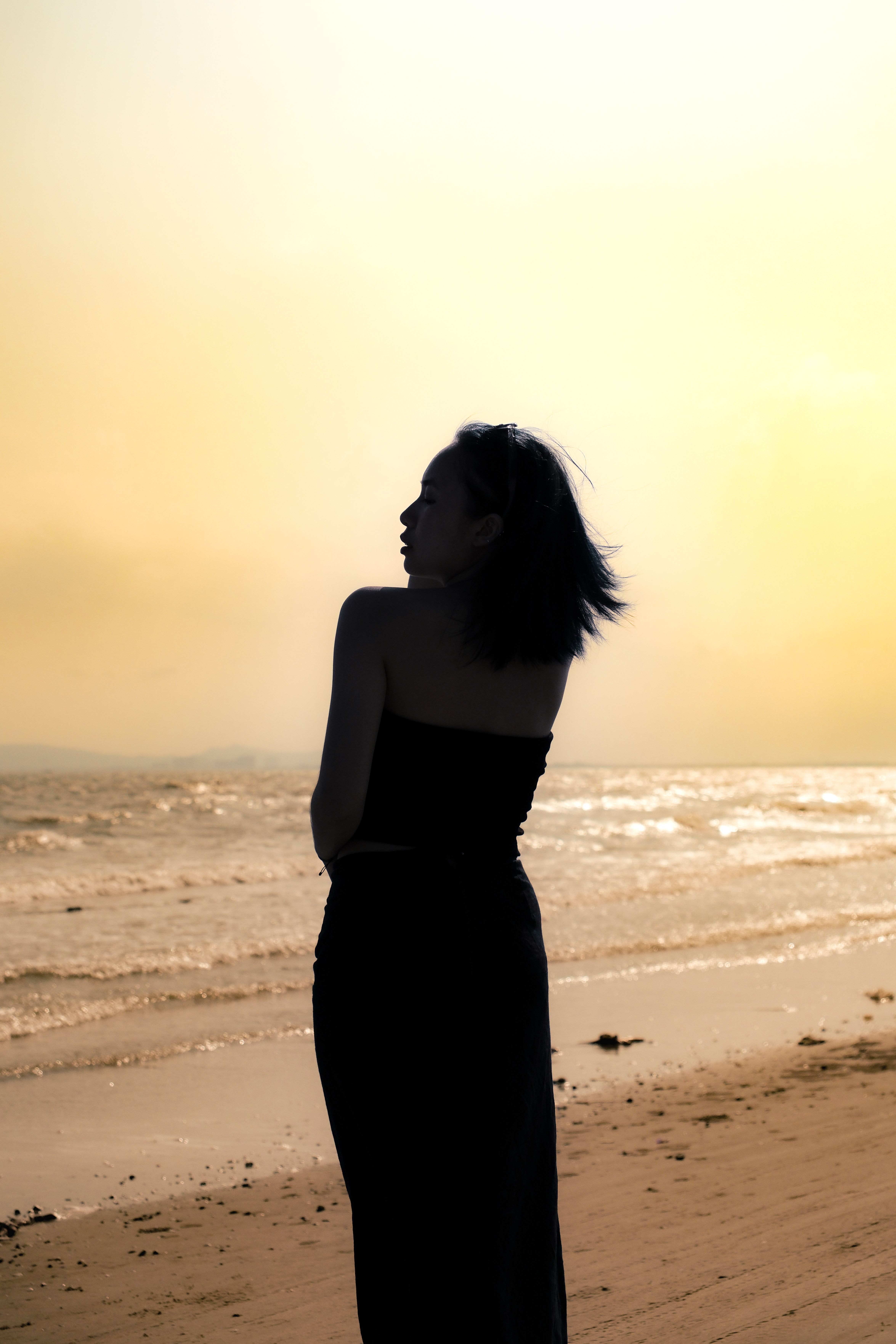 Silhouette of a woman against the golden sky at a peaceful Vietnamese beach during sunset.