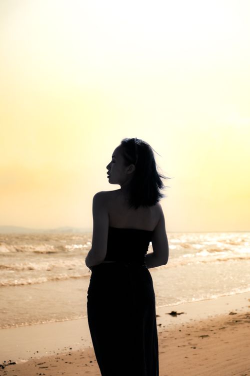 Free Silhouette of a woman enjoying a serene sunset at a Vietnamese beach. Stock Photo