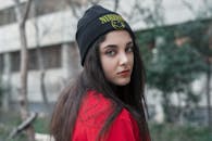 一个表情严肃的女人在户外摆姿势，背景是一个黑色的小人和红色的顶部